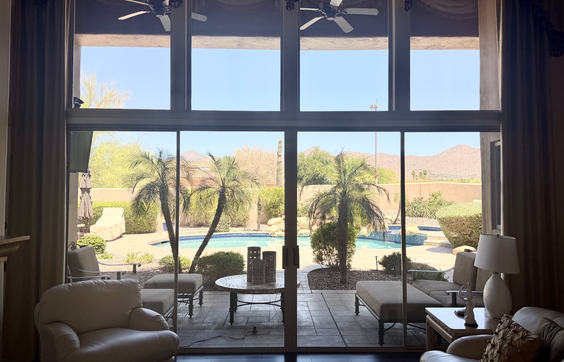 Clear view through sliding glass doors to a pool and desert mountains