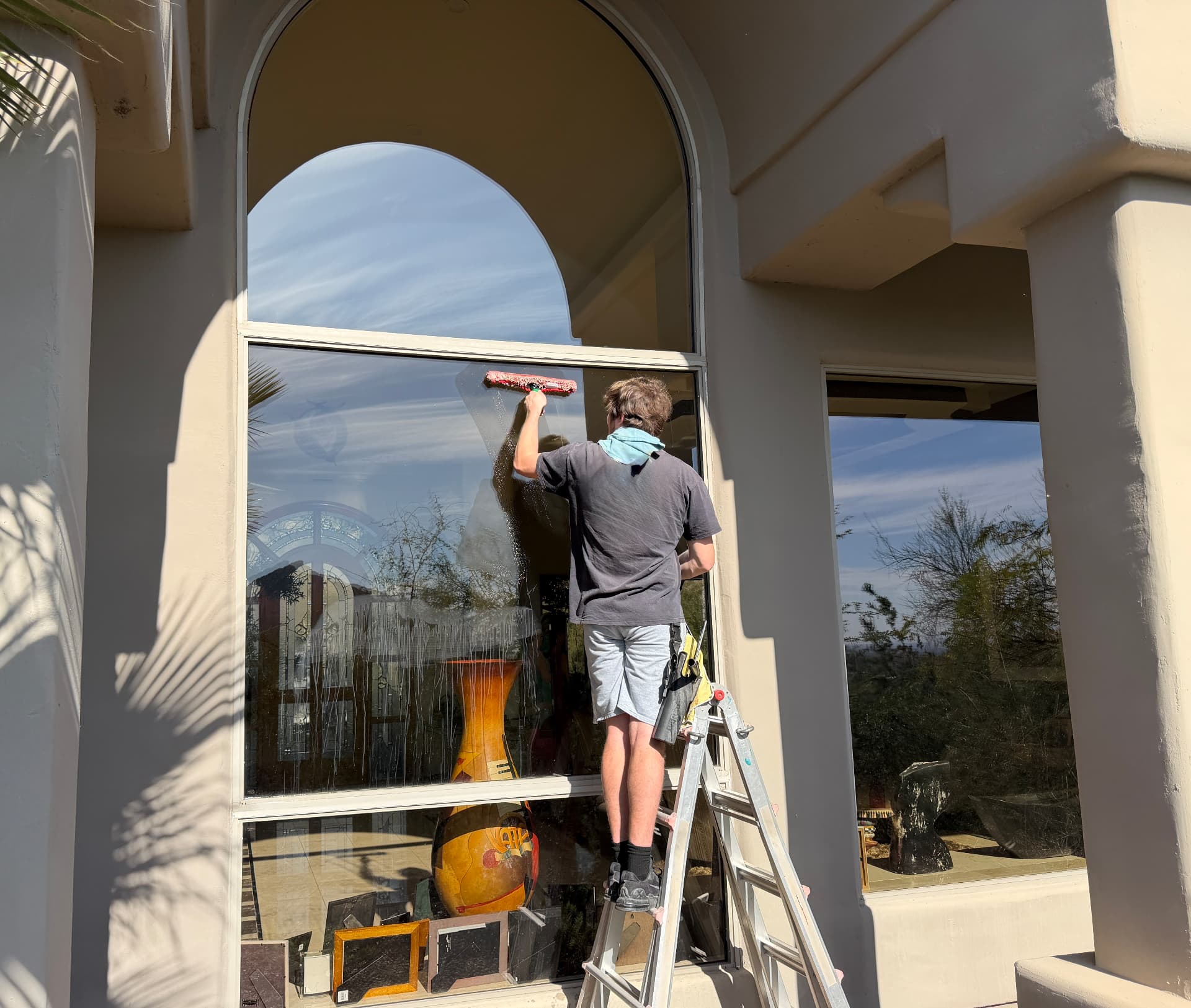 Squeegeeing a tall arched window on a Scottsdale, Arizona home